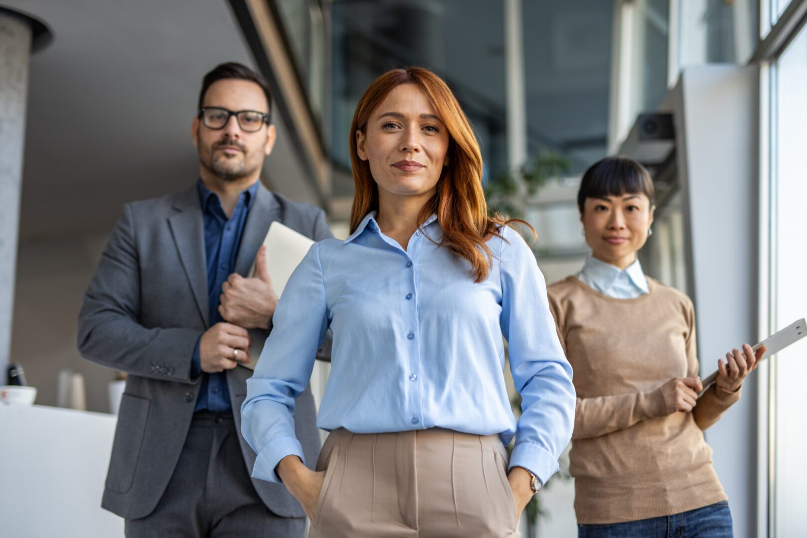 Three professionals standing confidently in an office.