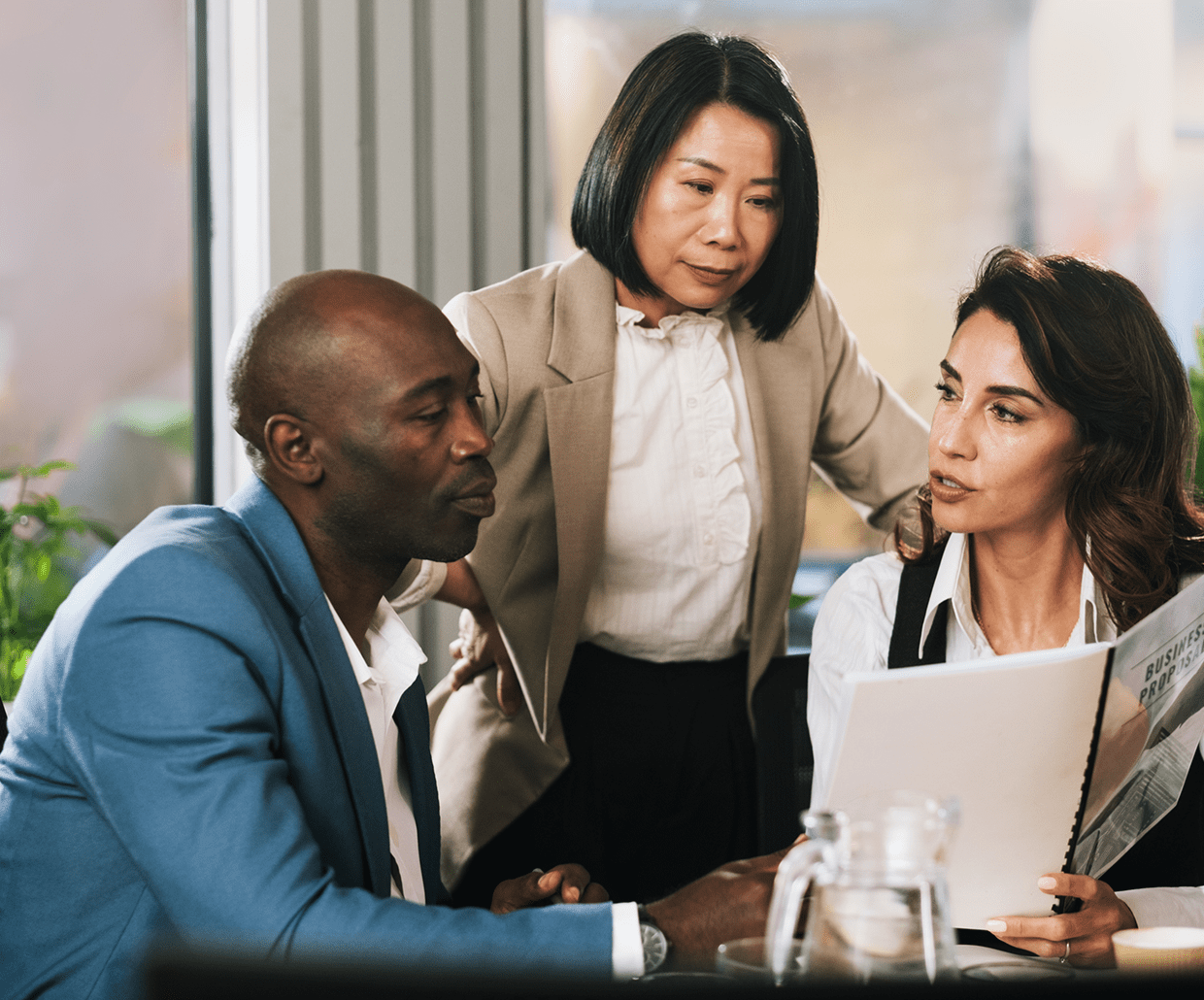 Three colleagues discussing a document together.
