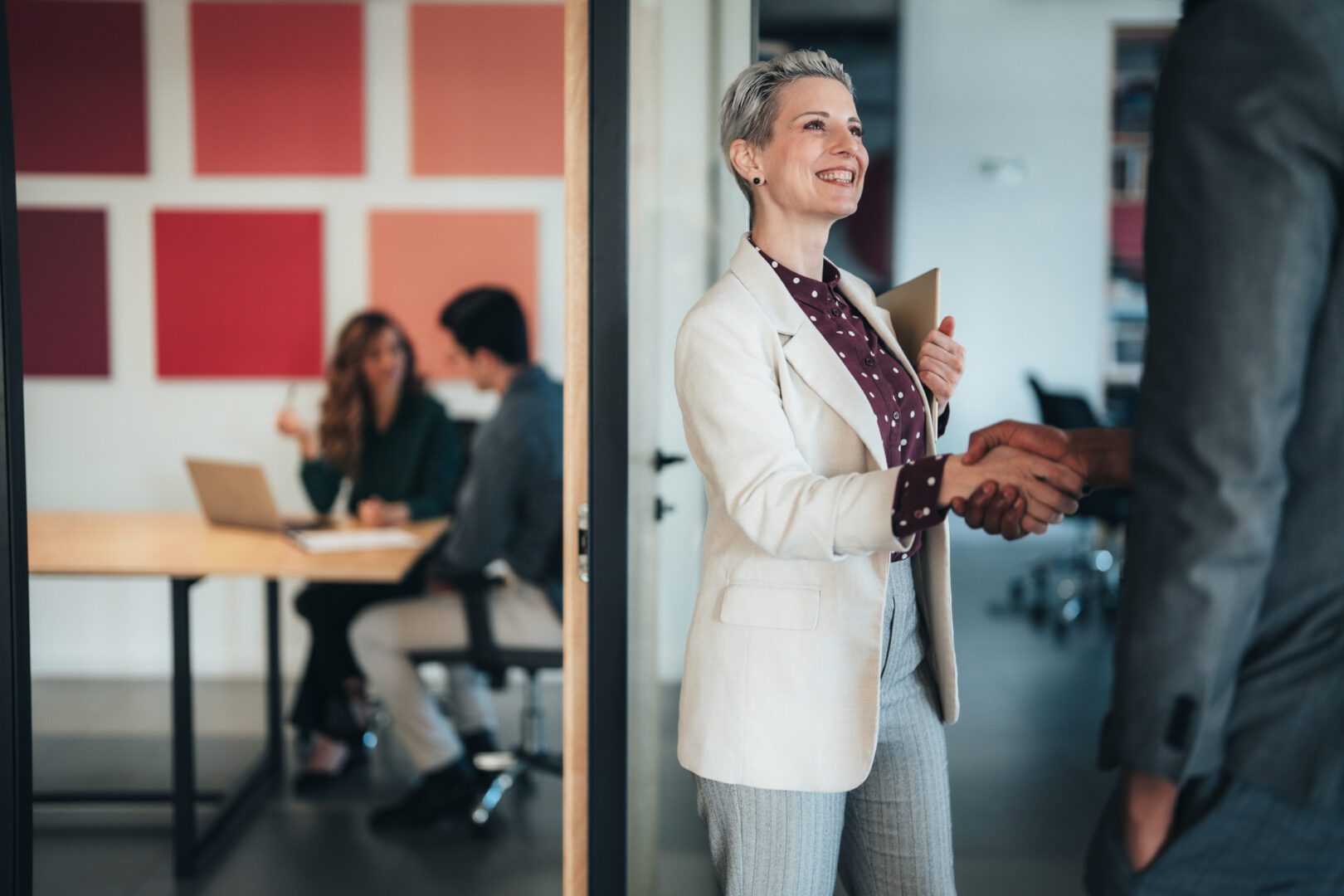 Businesswoman shaking hands in office meeting.