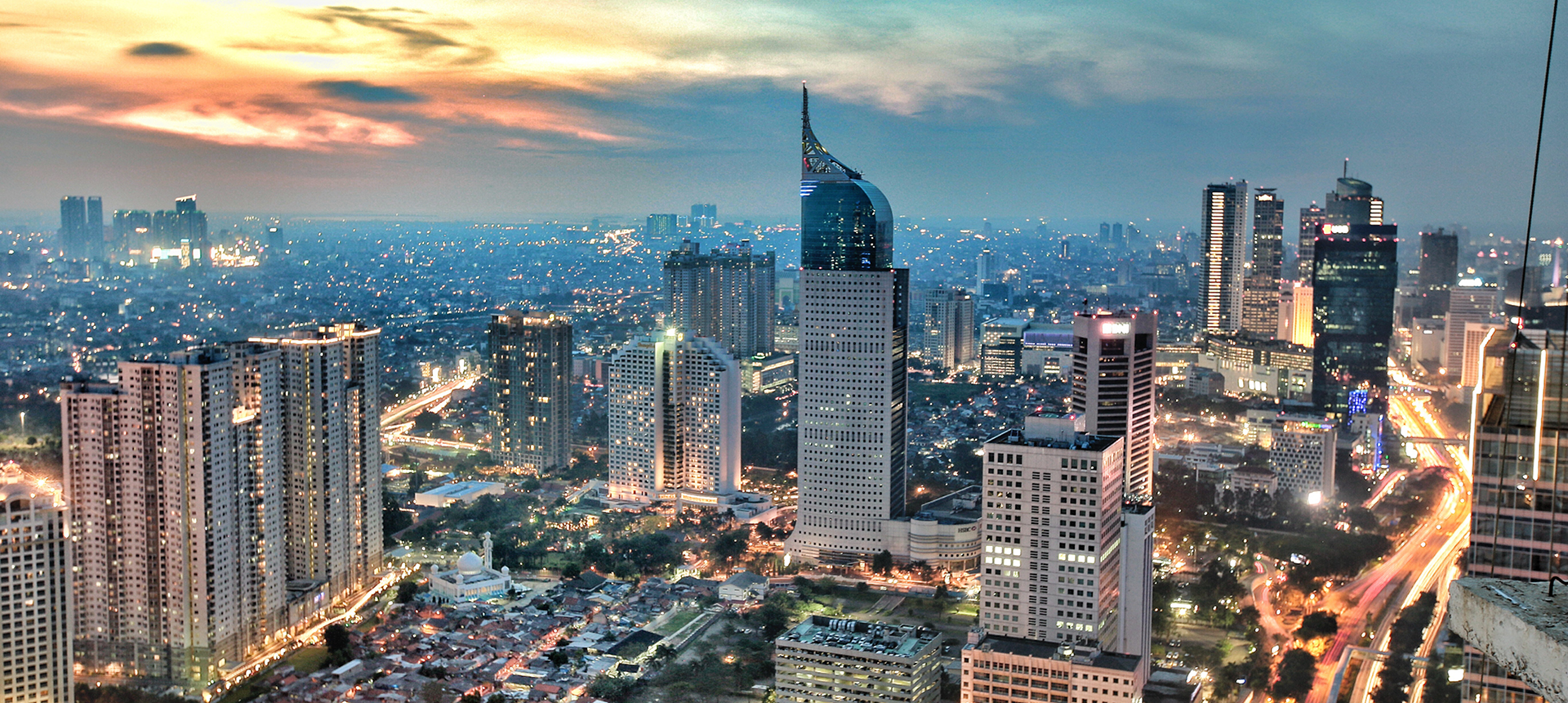 Jakarta skyline at sunset with city lights.